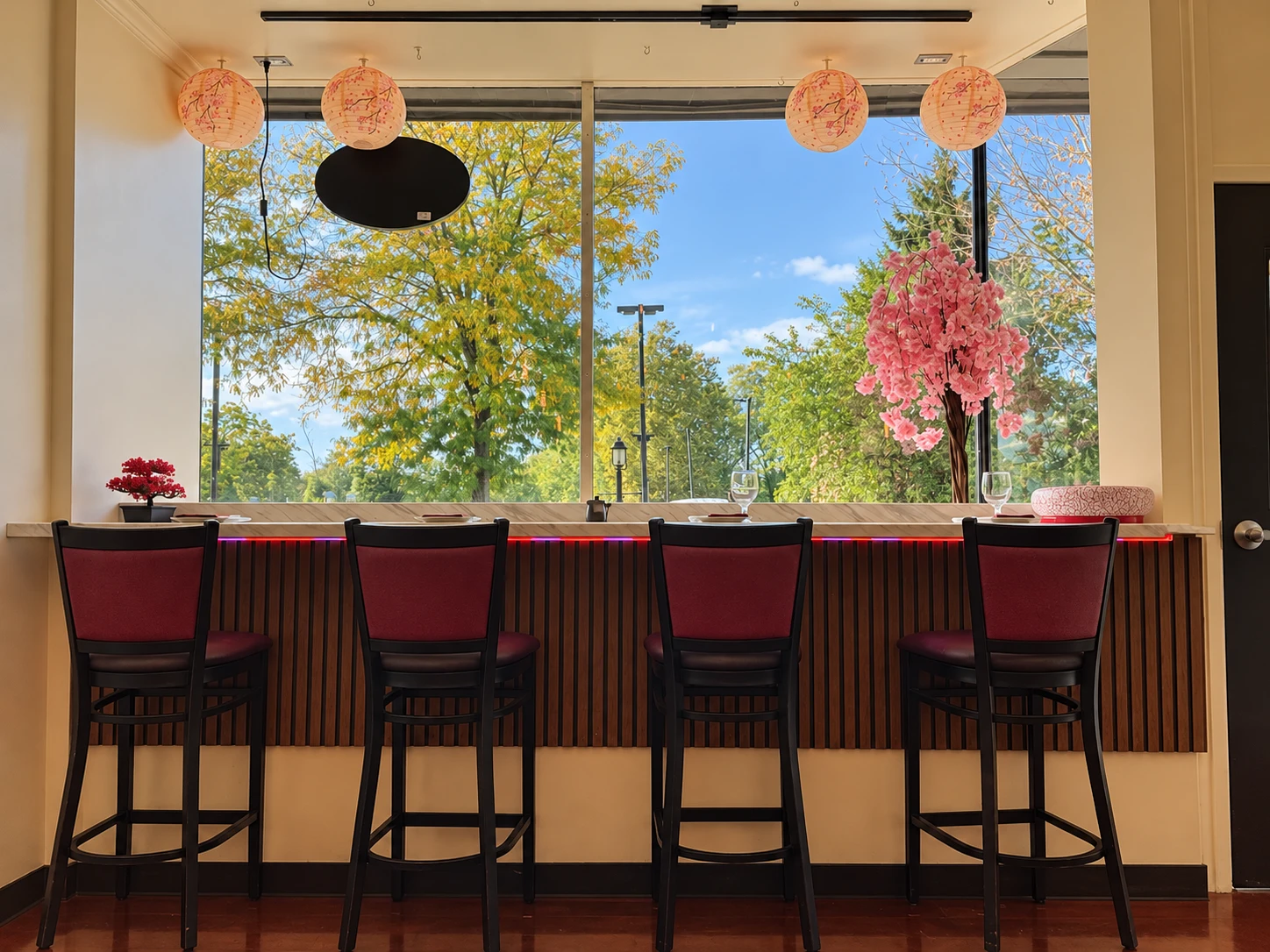 Nakama restaurant counter with burgundy chairs, paper lanterns and a cherry blossom tree